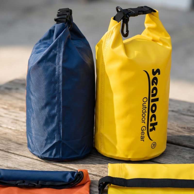 Lightweight coated polyester dry bag beside a 500D PVC dry bag with high-frequency welded seams
